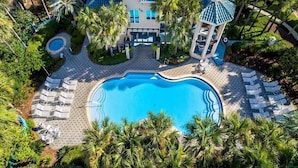 Un complexe hôtelier doté d’une grande piscine, de chaises longues, de palmiers et d’un bâtiment avec un toit bleu.