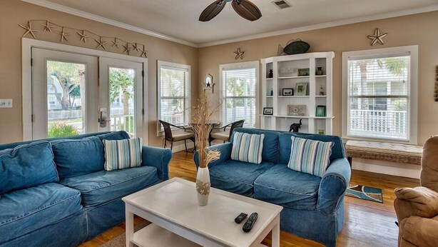 A living room with two blue sofas, a white coffee table, and a bookshelf.