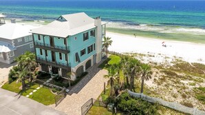 Un bâtiment à deux étages, doté d’une façade bleu clair et d’un toit blanc, situé près d’une plage au rivage sablonneux, offrant une vue sur l’océan.
