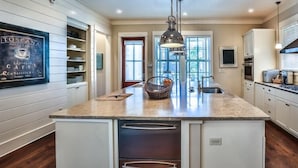 A kitchen with a central island, white cabinetry, and a hanging light fixture. - The Flagship of Watersound 5 Bedroom Holiday Home by Five Star Properties (Santa Rosa Beach)