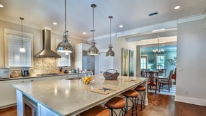 A spacious kitchen with a large island, pendant lighting, and a view into the dining area. - The Flagship of Watersound 5 Bedroom Holiday Home by Five Star Properties (Santa Rosa Beach)