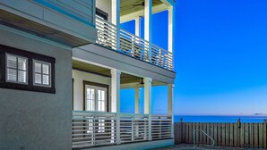 Un immeuble de deux étages doté d’un balcon, d’une piscine et offrant une vue sur l’océan.
