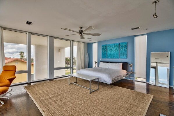Un dormitorio moderno con una cama grande, un ventilador de techo y vistas al exterior.
