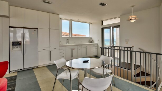 A modern kitchen with white cabinets, a built-in refrigerator, and a dining area with a round table and white chairs. - The White House of Holiday Isle 6 Bedroom Holiday Home by Five Star Properties (Destin)