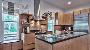 Una cocina moderna con armarios de madera, un refrigerador de acero inoxidable y una isla central con un lavamanos.
