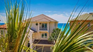 A two-story house with a balcony, a garage, and a view of the ocean. - Tuscan Villa 5 Bedroom Holiday Home by Five Star Properties (Destin)