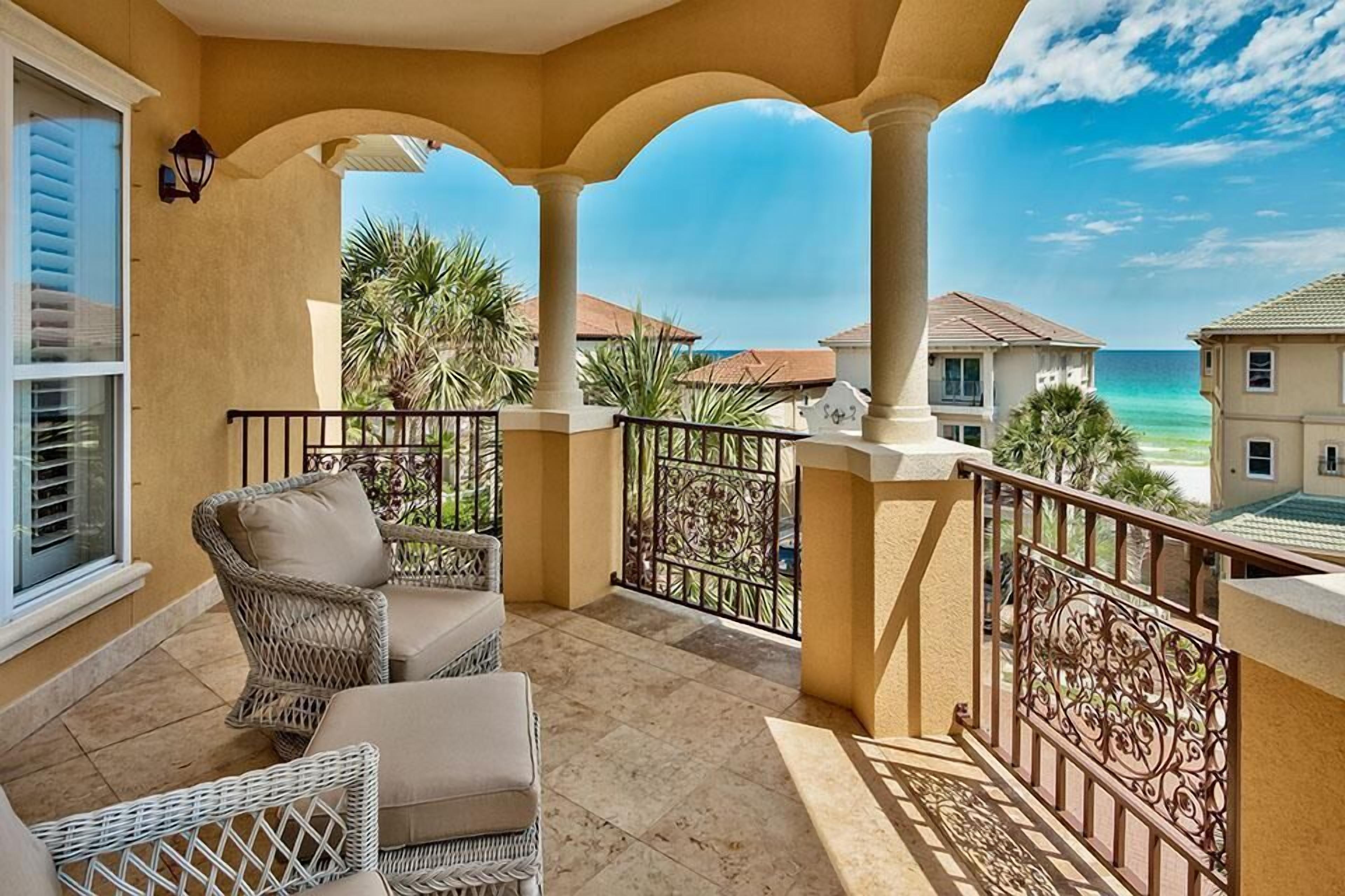 A balcony with wicker furniture, a view of the ocean, and a clear sky.