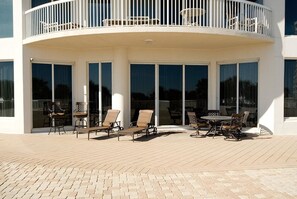 Eine überdachte Terrasse mit runder Balkonlage, großen Schiebeglastüren und Gartenmöbeln.
