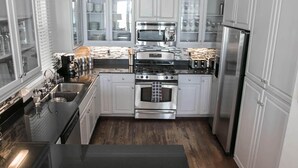 A modern kitchen with white cabinets, stainless steel appliances, and a black countertop. - Ventanas al Paraiso 5 Bedroom Holiday Home by Five Star Properties (Miramar Beach)