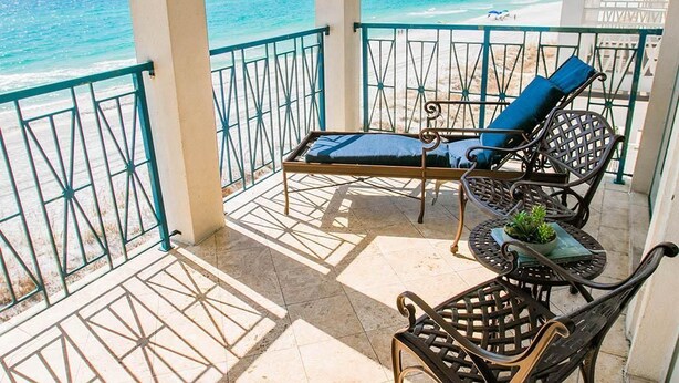 A balcony with a view of the ocean, featuring a lounge chair, a small table with a plant, and a metal railing. - Ventanas al Paraiso 5 Bedroom Holiday Home by Five Star Properties (Miramar Beach)