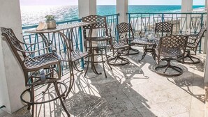 A covered outdoor seating area with metal chairs and tables, overlooking a beach. - Ventanas al Paraiso 5 Bedroom Holiday Home by Five Star Properties (Miramar Beach)
