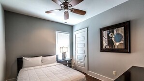 A bedroom with a bed, a ceiling fan, a door, and a framed artwork on the wall. - VILLA DEL CARMEN 5 Bedroom Holiday Home by Five Star Properties (Miramar Beach)