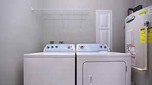A laundry room with two white front-loading washers and dryers, a white door, and a white refrigerator with a water dispenser. - VILLA DEL CARMEN 5 Bedroom Holiday Home by Five Star Properties (Miramar Beach)