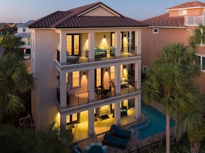 A multi-story hotel with balconies, a swimming pool, and outdoor seating areas.