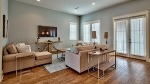 A spacious living room with a beige sofa, a coffee table, and a TV mounted on the wall. - Villa Destiny 6 Bedroom Holiday Home by Five Star Properties (Destin)
