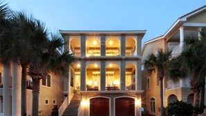 A two-story building with a symmetrical facade, large arched windows, and a central staircase leading to the upper floor.