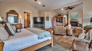 A spacious bedroom with a large bed, a television, and a fireplace.