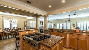 A spacious kitchen with a central island, wooden cabinets, and a granite countertop.