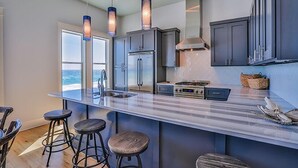 A modern kitchen with a large island, stainless steel appliances, and bar stools.