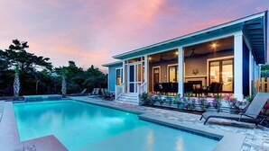 Une piscine avec un patio couvert, des chaises longues et une vue sur la piscine.