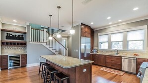 Une cuisine moderne dotée d’un îlot central, de sièges de bar et d’un escalier menant à un niveau supérieur.