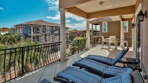 A balcony with sun loungers, a covered seating area, and a view of neighboring houses. - Honu Hale 5 Bedroom Holiday Home by Five Star Properties (Destin)