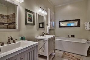 A bathroom with two sinks, a large bathtub, and multiple mirrors.