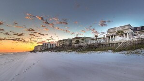Hotel frente a la playa con arena y vista al atardecer.