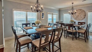 Un comedor con una mesa grande, varias sillas y detalles decorativos como un candelabro y cuadros en la pared.