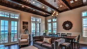 A spacious living area with a large sofa, a dining table, and a chandelier. - Kates Porch 7 Bedroom Holiday Home by Five Star Properties (Miramar Beach)