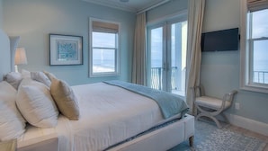 Una camera da letto con un letto grande, una sedia, una TV e vista sull'oceano.