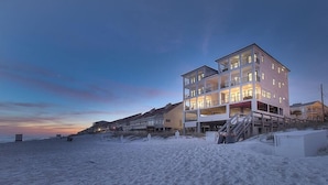 Un edificio a più piani fronte spiaggia, con balconi e una scala che conduce alla spiaggia.