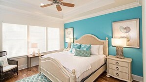 A bedroom with a bed, a nightstand, a chair, a ceiling fan, and a window with blinds. - LA TERRAZZA 948A 4 Bedroom Holiday Home by Five Star Properties (Miramar Beach)