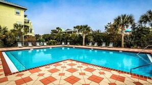 A swimming pool with a tiled deck, surrounded by palm trees and lounge chairs. - LA TERRAZZA 948A 4 Bedroom Holiday Home by Five Star Properties (Miramar Beach)