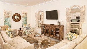 A living room with a sofa set, a coffee table, a TV, and decorative wall art. - LA TERRAZZA 948A 4 Bedroom Holiday Home by Five Star Properties (Miramar Beach)