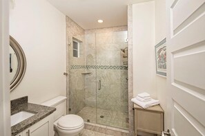 Un baño con inodoro, lavamanos y zona de ducha.