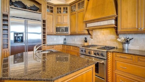 A kitchen with granite countertops, stainless steel appliances, wooden cabinets, and a built-in oven. - Laissez Faire 5 Bedroom Holiday Home by Five Star Properties (Santa Rosa Beach)