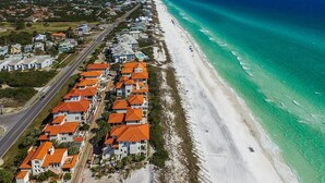 An aerial view of a coastal residential area with houses along the beach, a road parallel to the shore, and clear blue waters. - Laissez Faire 5 Bedroom Holiday Home by Five Star Properties (Santa Rosa Beach)