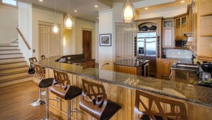 A modern kitchen with a central island, bar stools, stainless steel appliances, and pendant lighting. - Laissez Faire 5 Bedroom Holiday Home by Five Star Properties (Santa Rosa Beach)