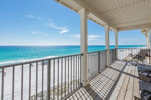 A wooden deck with a view of the beach and ocean.