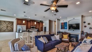 A spacious living room with a blue sofa, striped armchairs, and a fireplace.