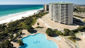 Ein Resort mit großem Pool, Strand und einem hohen Hotelgebäude.
