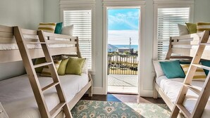 A room with bunk beds, a view of the beach, and a balcony with a railing. - Looking Glass 5 Bedroom Holiday Home by Five Star Properties (Santa Rosa Beach)