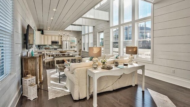 A spacious living area with a large window, a dining table, and a cozy seating arrangement. - Looking Glass 5 Bedroom Holiday Home by Five Star Properties (Santa Rosa Beach)