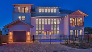 A multi-story house with a garage, large windows, and a fenced backyard. - Looking Glass 5 Bedroom Holiday Home by Five Star Properties (Santa Rosa Beach)