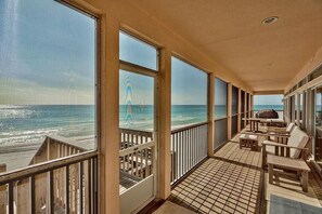 Een balkon met uitzicht op de oceaan, houten meubels en een betegelde vloer.