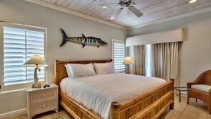 A bedroom with a large bed, two bedside tables, a ceiling fan, and a fish wall decoration. - Luna Sea 4 Bedroom Holiday Home by Five Star Properties (Santa Rosa Beach)