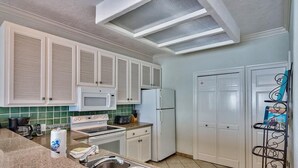A kitchen with white cabinets, a microwave, a refrigerator, and a sink. - Luna Sea 4 Bedroom Holiday Home by Five Star Properties (Santa Rosa Beach)