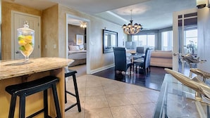 A modern kitchen with a marble countertop, black bar stools, and a glass-top dining table. - MEDITERRANEA 401A 3 Bedroom Holiday Home by Five Star Properties (Miramar Beach)