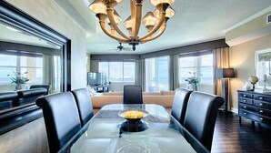 A modern dining area with a glass table, leather chairs, and a chandelier. - MEDITERRANEA 401A 3 Bedroom Holiday Home by Five Star Properties (Miramar Beach)